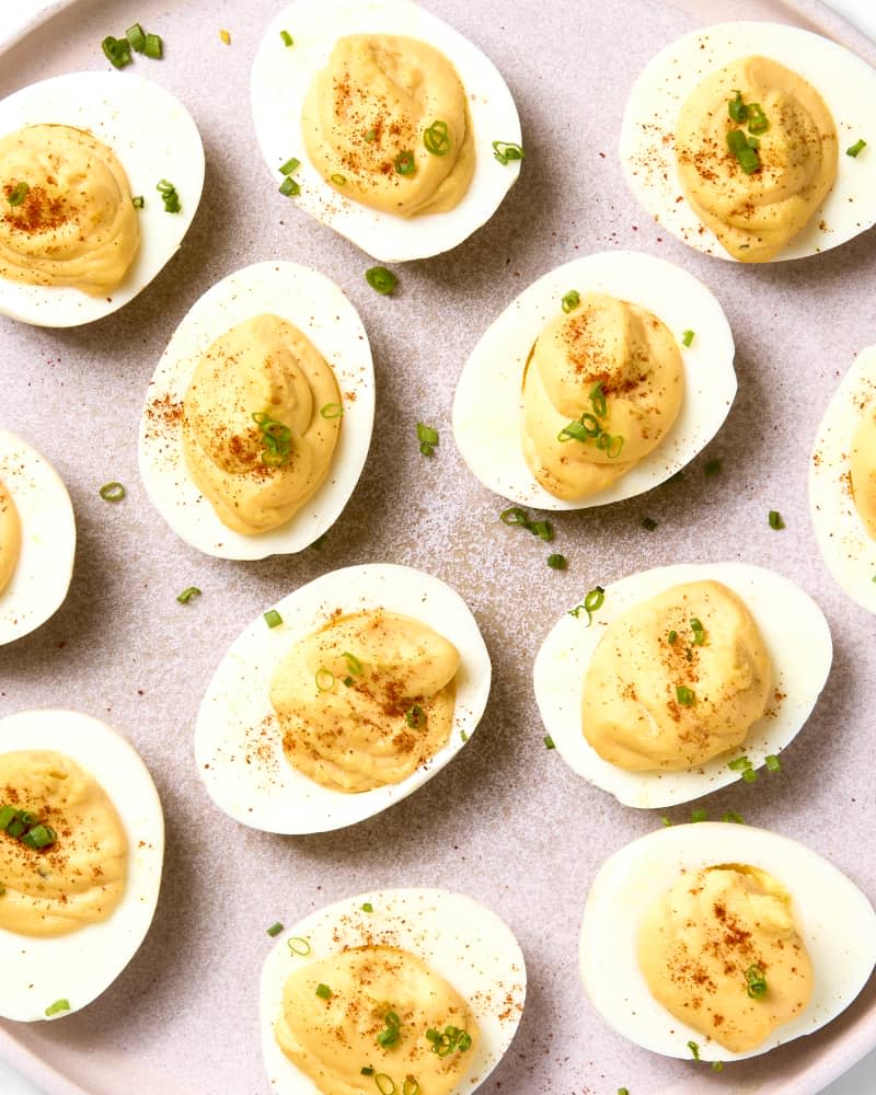 overhead shot of deviled eggs on a light pink plate, topped with toasted panko, green onion and paprika.