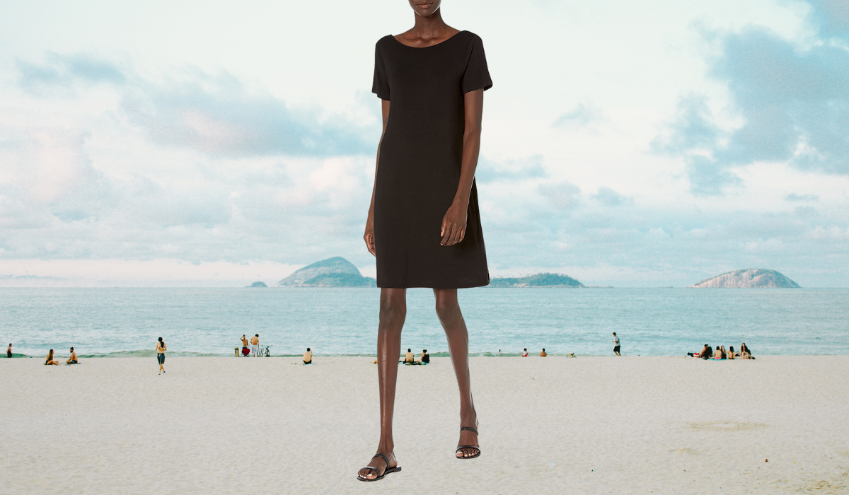 A woman wearing a mid-length loose black t-shirt dress and black sandals