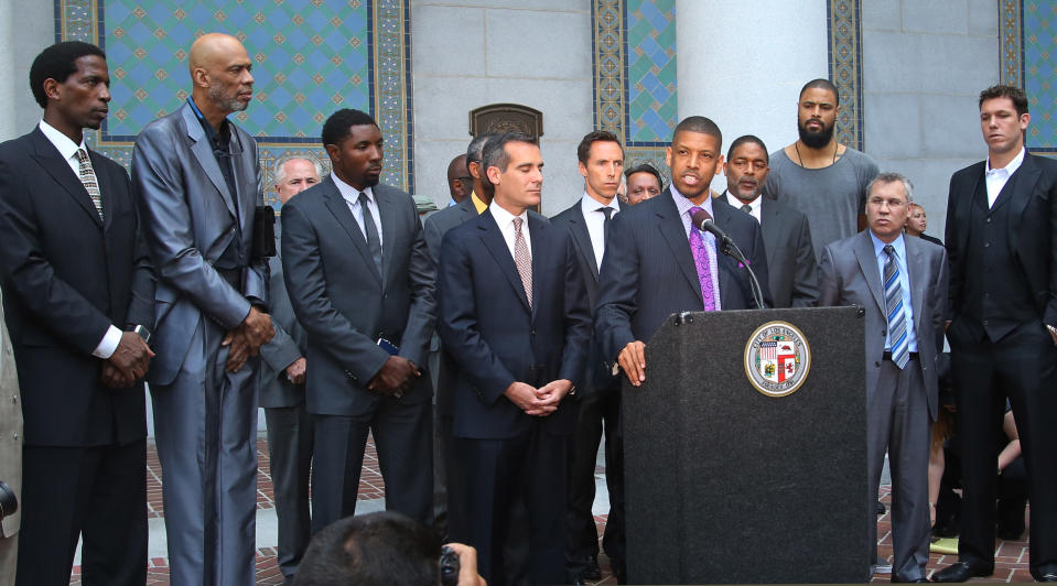In this photo takenon April 29, 2014 photo, Sacramento, Calif., Mayor Kevin Johnson, at podium, with Los Angeles Mayor Eric Garcetti to his left, speaks about the penalties imposed on Los Angeles Clippers owner Donald Sterling by the NBA during a news conferences at Los Angeles City Hall. From left are current and former NBA players A.C. Green, Kareem Abdul-Jabbar, Roger Mason Jr., Steve Nash, Norm Nixon, Tyson Chandler (tall, bearded) and Luke Walton, far right. Last year Johnson almost single-handedly kept the Kings NBA franchise in Sacramento, staging a late-game comeback to snatch the team away from a Seattle billionaire. This spring he began raising his national political profile by taking over as the head of the U.S. Conference of Mayors, then acting as spokesman for the NBA players as the controversy over racist remarks by the Clippers' owner threatened to throw the basketball league into turmoil. (AP Photo/Nick Ut)