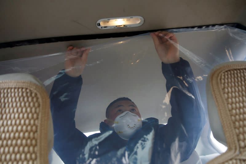 Staff member installs plastic shield inside a vehicle at a service centre of car-hailing service Didi Chuxing, as the country is hit by an outbreak of the new coronavirus, in Beijing