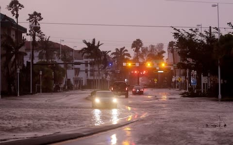 Vehicles drive through a flooded street as Hurricane Irma passes through Naples, Florida - Credit: AP