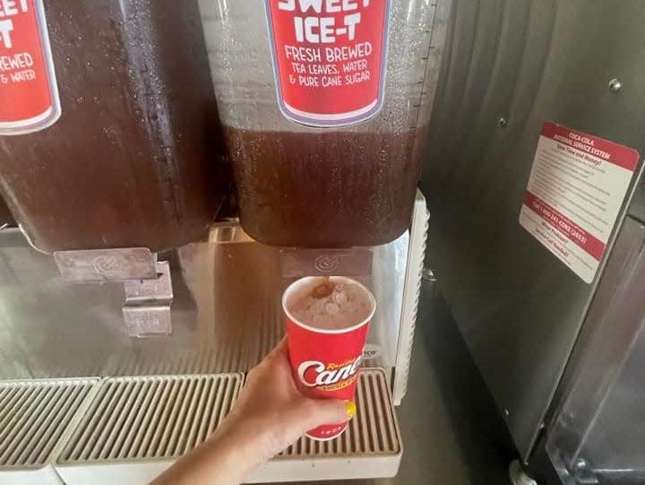 The writer holds a cup with as she dispenses sweet tea at Raising Cane's