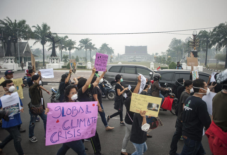 Activists hold posters as they march during a protest urging the government to speed up their action to tackle forest fires in Palangkaraya, Central Kalimantan, Indonesia, Friday, Sept. 20, 2019. Haze blown by monsoon winds from fires in Indonesia has begun affecting some areas of the Philippines and raised concerns about aviation safety and possible health risks, an official said Friday. (AP Photo/Fauzy Chaniago)