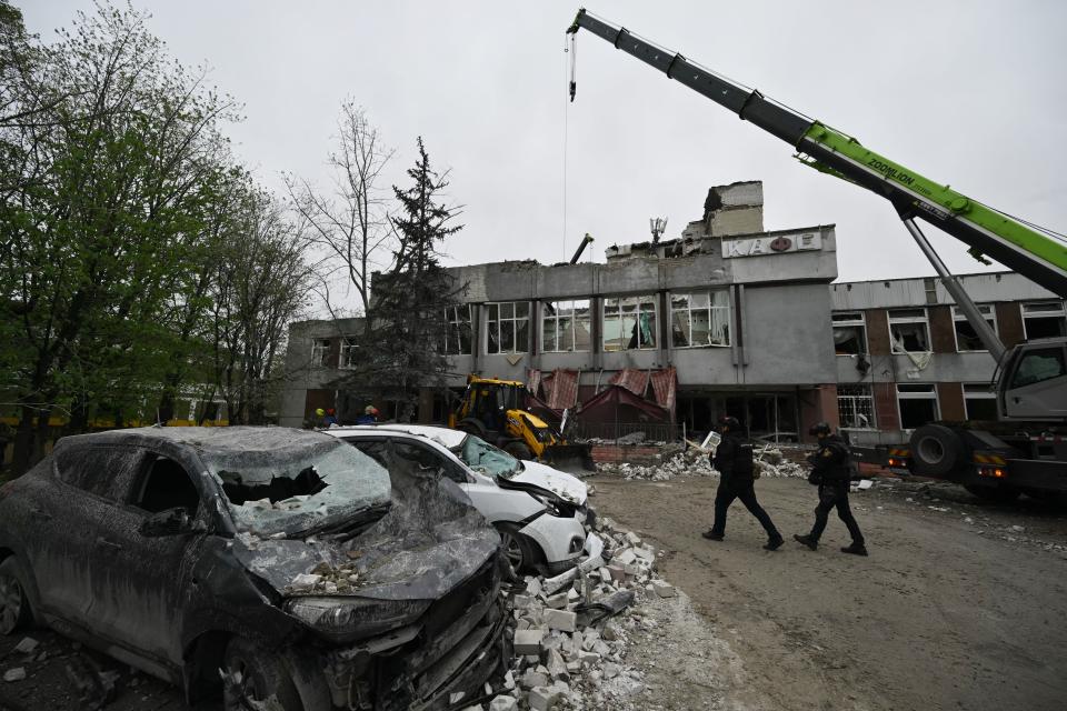 Ukrainian law enforcement officers walk past destroyed cars at the site of a missile attack in Chernigiv on April 17, 2024, amid the Russian invasion of Ukraine.