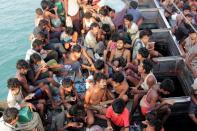 Rohingya migrants sit in their boat as they are towed closer to land by Acehnese fishermen off the coast of Geulumpang in Indonesia's Aceh province, on May 20, 2015