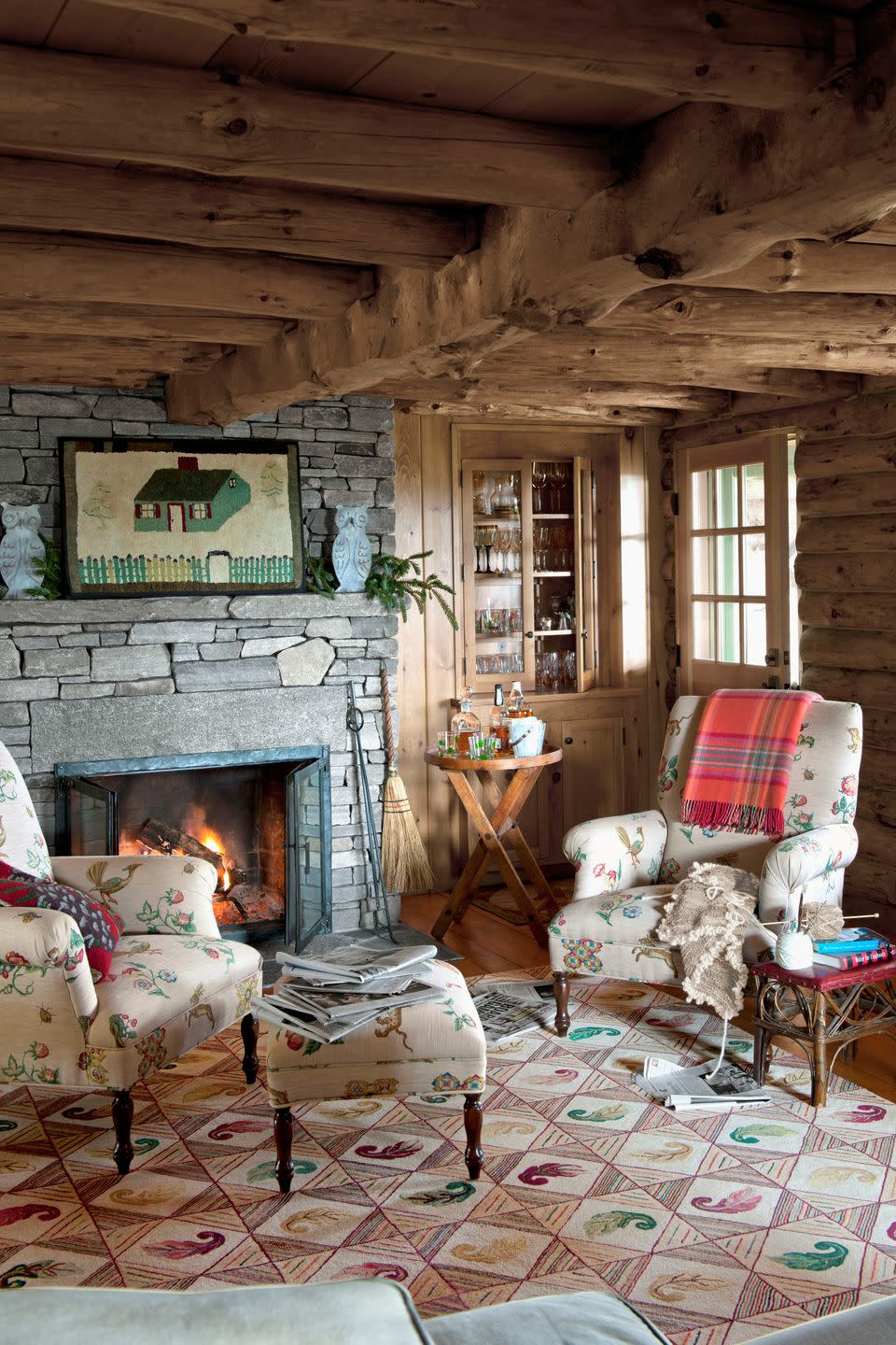 a living room with a pair of chairs and a stone fireplace