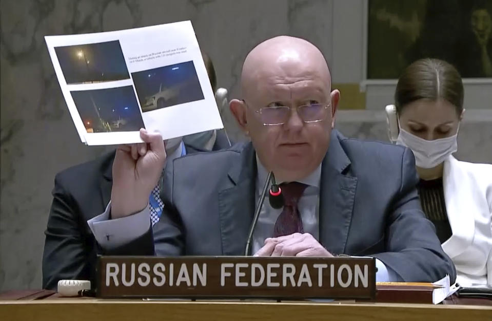 Russian Ambassador to the United Nations Vasily Nebenzya holds up copies of photos while speaking during a Security Council meeting, Friday, March 11, 2022, at UN headquarters. The Russian request for the Security Council meeting followed a U.S. rejection of Russian accusations that Ukraine is operating chemical and biological labs with U.S. support. (UNTV via AP)