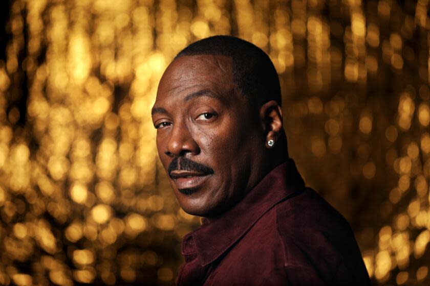 Eddie Murphy looks over his shoulder in front of a golden backdrop