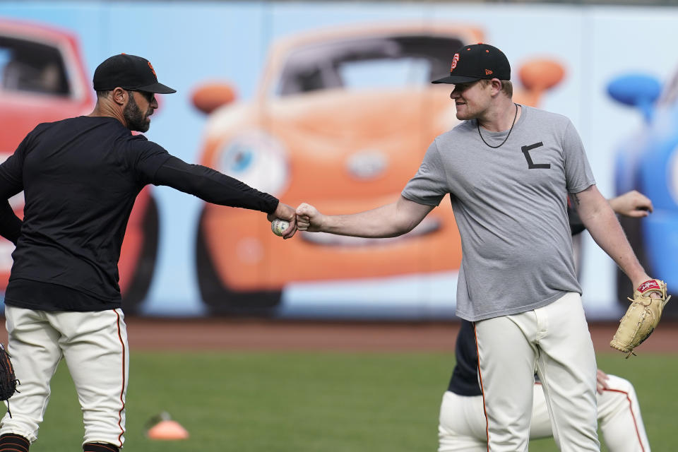 San Francisco Giants manager Gabe Kapler, left, greets pitcher Logan Webb during a baseball practice in San Francisco, Tuesday, Oct. 5, 2021. (AP Photo/Jeff Chiu)