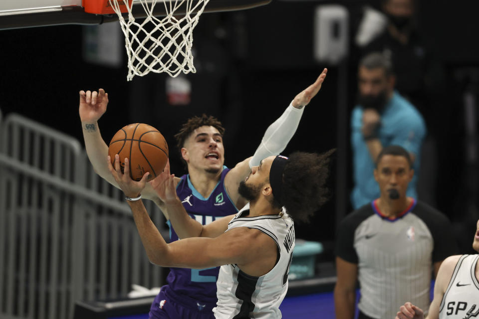 San Antonio Spurs guard Derrick White, right, drives to the basket against Charlotte Hornets guard LaMelo Ball during the first half of an NBA basketball game in Charlotte, N.C., Sunday, Feb. 14, 2021. (AP Photo/Nell Redmond)