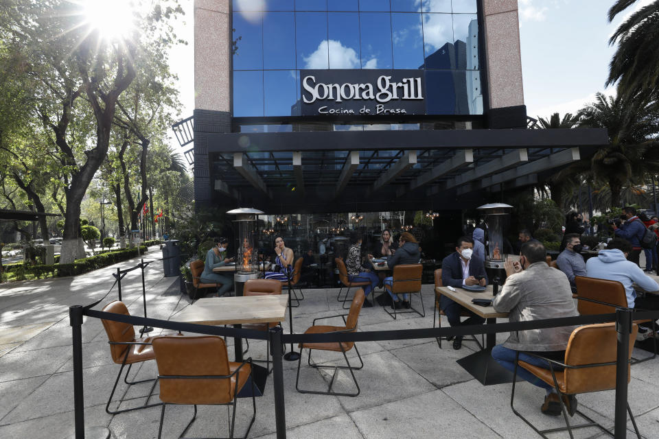 Diners eat at outdoor tables at a branch of Sonora Grill on Paseo de la Reforma in Mexico City, Monday, Jan. 11, 2021. More than three weeks into Mexico City's second pandemic shutdown some restaurateurs worried about their ability to survive ignored official warnings and opened limited seating Monday under the slogan "Abrir o Morir," Spanish for "Open or Die." (AP Photo/Rebecca Blackwell)