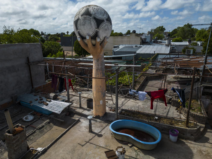 A water tank made to look like a large hand holding a soccer ball stands on the roof of a house recalling the famous goal Diego Maradona scored with his hand against England in the 1986 World Cup, in the La Cumbre neighborhood on the outskirts of La Plata, Argentina, Tuesday, Oct. 18, 2022. The structure, built by a bricklayer known as "Tiki" by the neighbors, memorializes Maradona's famous goal that came to be known as the "Hand of God." (AP Photo/Rodrigo Abd)