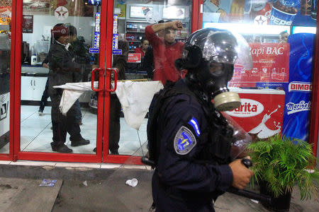 Supporters of Salvador Nasralla, presidential candidate for the Opposition Alliance Against the Dictatorship, stand inside at a convenience store as a policeman patrols during a protest to demand the official presidential election results, outside the warehouse of the Supreme Electoral Tribunal in Tegucigalpa, Honduras November 30, 2017. REUTERS/Jorge Cabrera