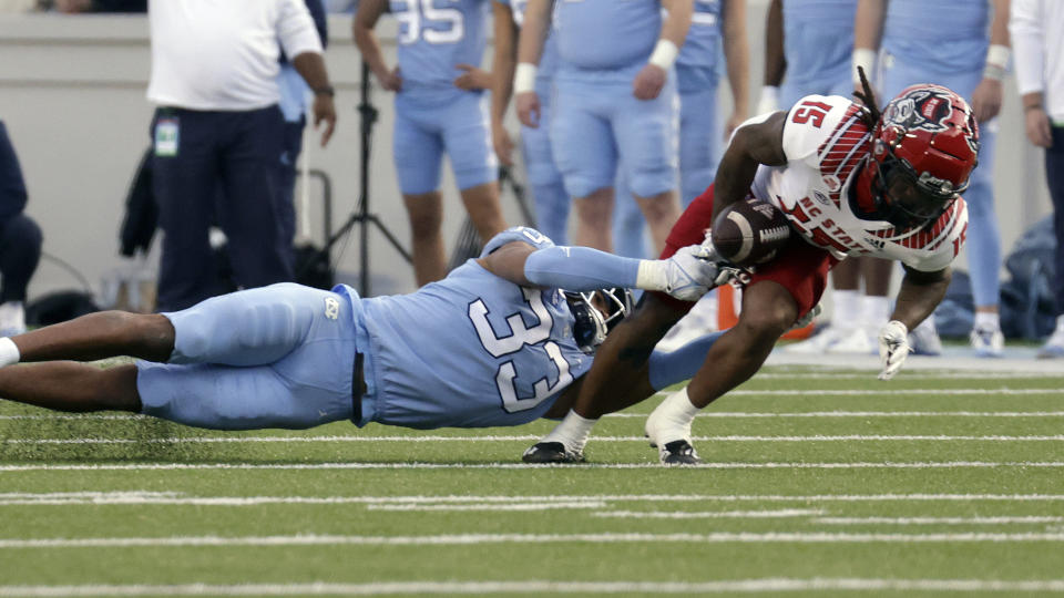 North Carolina State wide receiver Keyon Lesane (15) fumbles the ball as he is hit by North Carolina linebacker Cedric Gray (33) during the first half of an NCAA college football game Friday, Nov. 25, 2022, in Chapel Hill, N.C. North Carolina State recovered the ball. (AP Photo/Chris Seward)