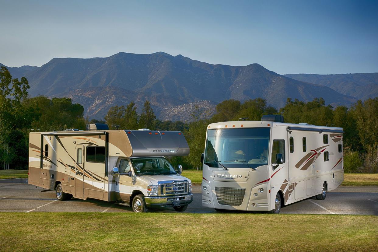 Winnebago Vista and Mini Winnie 2017 RV models, side by side in a parking lot surrounded by grass and forest, Ojai, California, mountains and blue sky in the background