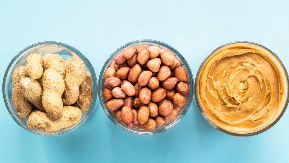 glass jars of peanuts and peanut butter on a blue background