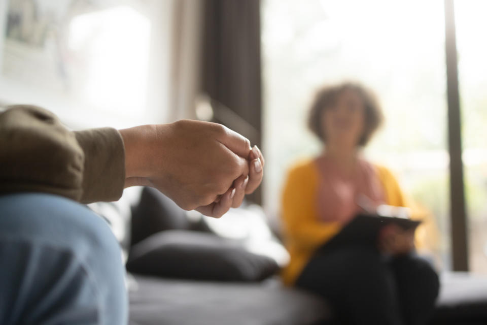 A therapist and client in a room, with the client sitting and the therapist blurred in the background