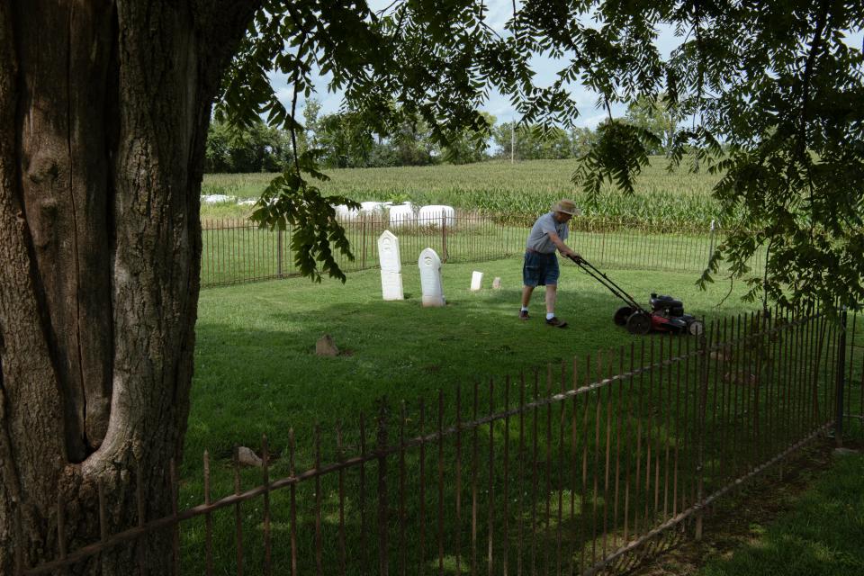 Jim Swinford mows the grass around his ancestors' graves in Berry, Kentucky, on Aug. 2, 2022.