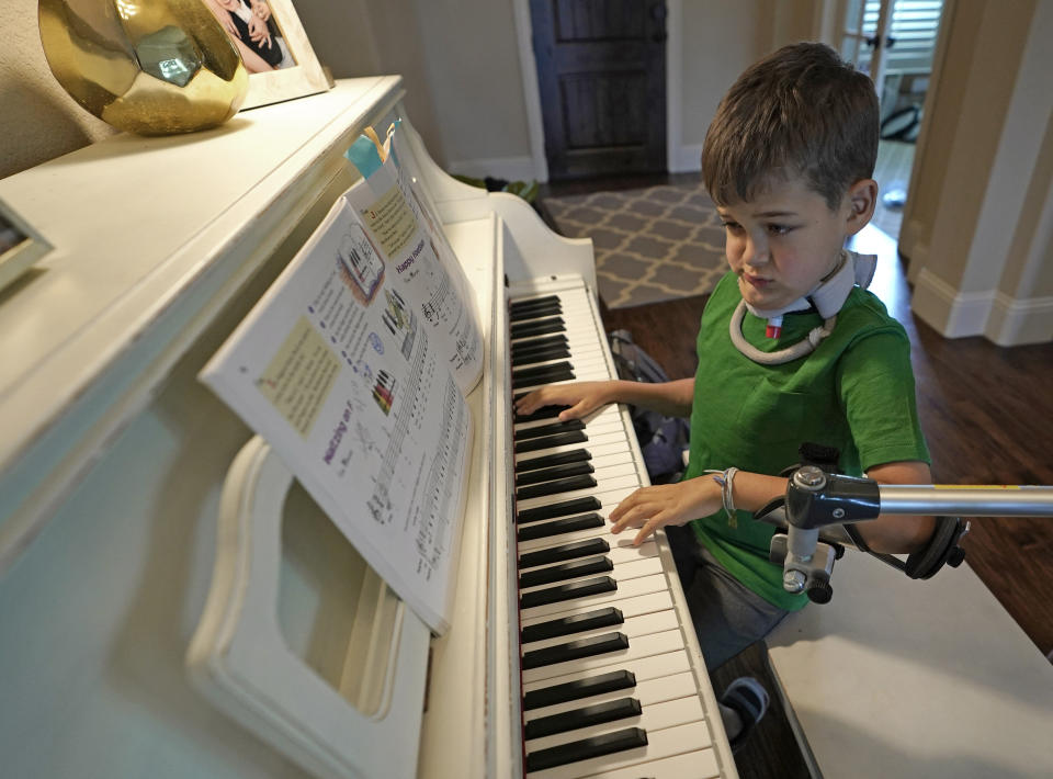 Braden Scott uses a device to support his left arm as he practices on the piano. (Photo: ASSOCIATED PRESS)