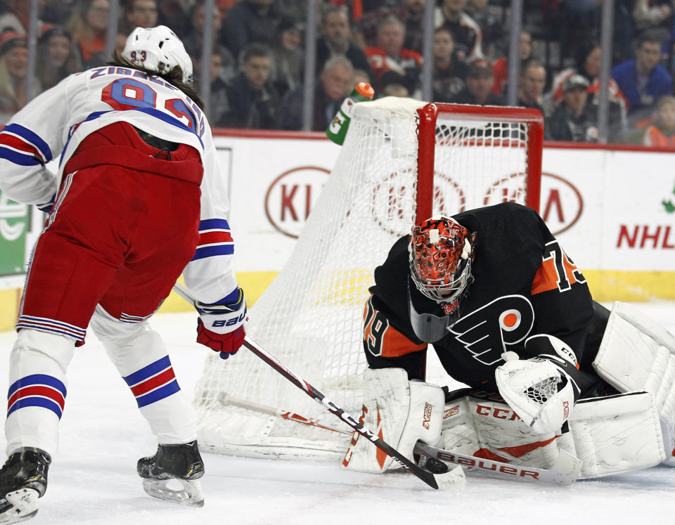 The shot on goal by New York Rangers' Mika Zibanejad, left, is stopped by Philadelphia Flyers' Carter Hart during the first period of an NHL hockey game, Monday, Dec. 23, 2019, in Philadelphia. (AP Photo/Tom Mihalek)