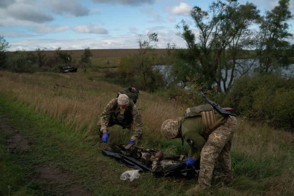 Ukrainian National Guard servicemen place the body of a Ukrainian soldier in a bag at an area near the border with Russia, in Kharkiv region, Ukraine (AP)