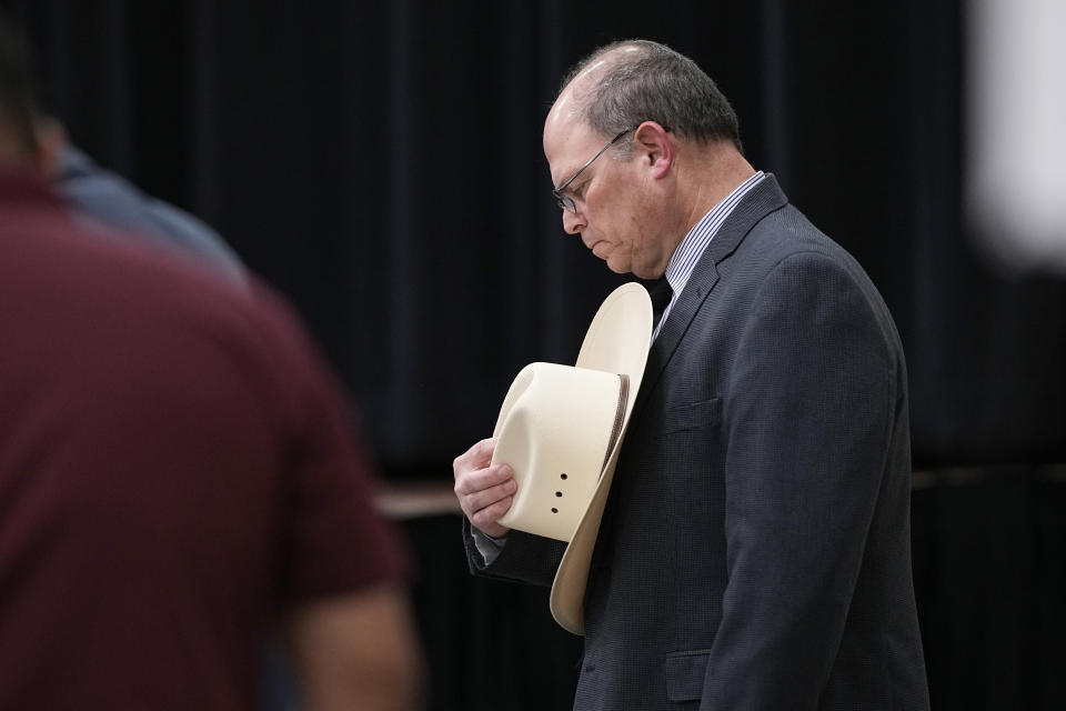 Jesse Prado, an Austin-based investigator, right, bows his head during a prayer before he shared his findings at a special city council meeting in Uvalde, Texas, Thursday, March 7, 2024. Almost two years after the deadly school shooting in Uvalde that left 19 children and two teachers dead, the city council met to discuss the results of an independent investigation it requested into the response by local police officers. (AP Photo/Eric Gay)