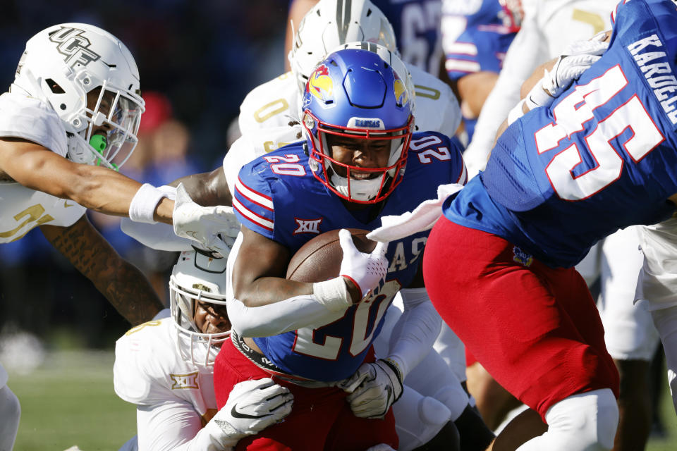 Kansas running back Daniel Hishaw Jr. (20) is stopped by several UCF defenders during the first half of an NCAA football game, Saturday, Oct. 7, 2023, in Lawrence, Kan. (AP Photo/Colin E. Braley)