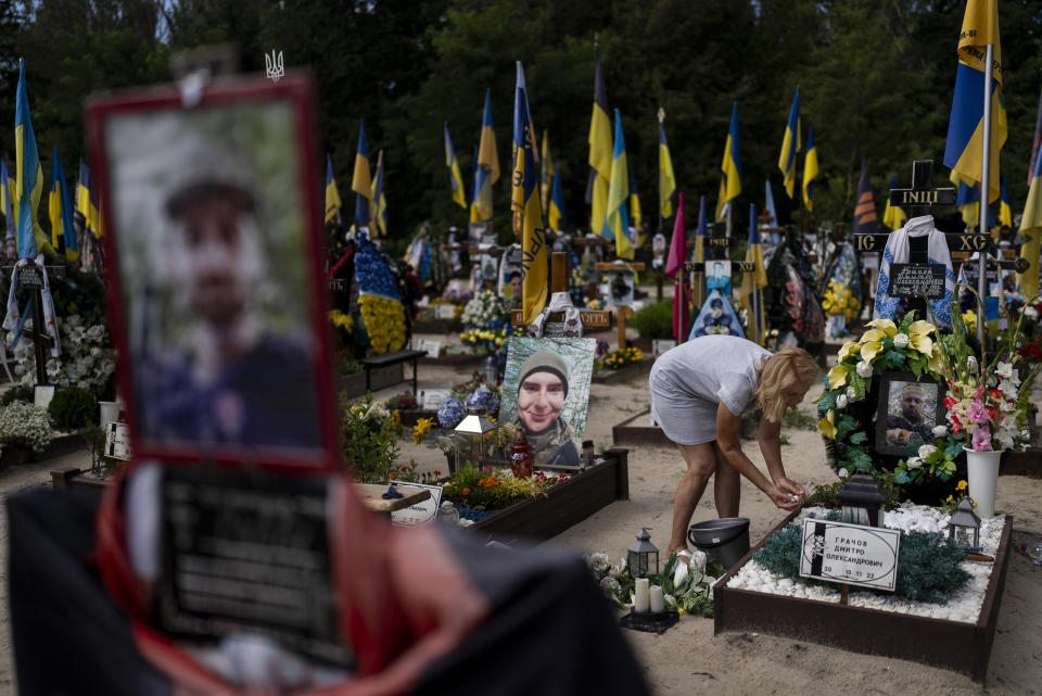Natalie Zaichenko, 60, tends to the grave of her son, a Ukrainian soldier who was killed in the war against Russia, in Kyiv, Ukraine, Thursday, Aug. 3, 2023. (AP Photo/Jae C. Hong)