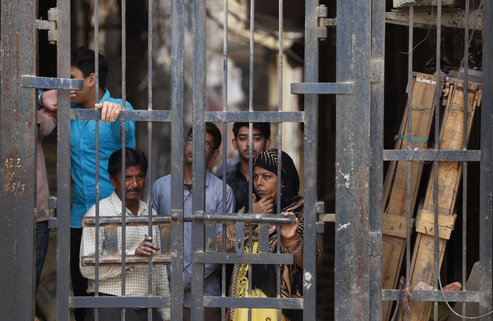 FILE - In this Thursday, Feb. 27, 2020, file photo, residents look from behind a closed iron gate of their alley in Karaval Nagar following Tuesday's violence in New Delhi, India. Indian police violated human rights during deadly religious riots in New Delhi earlier this year, Amnesty International said in a report released Friday, Aug. 28, 2020. It said police beat protesters, tortured detainees and in some cases took part in riots with Hindu mobs. Authorities say more than 50 people were killed when clashes broke out between Hindus and Muslims over a controversial citizenship law in February in the worst rioting in the Indian capital in decades. (AP Photo/Rajesh Kumar Singh, File)