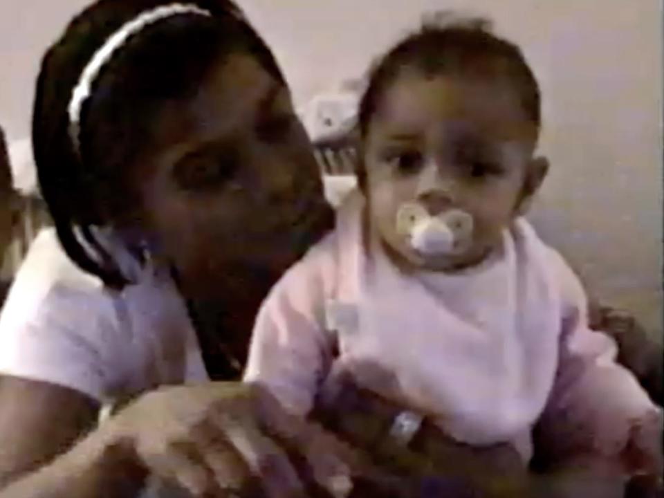 A baby Simone Biles with a pacifier and her biological mother from a home video.