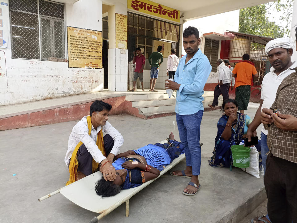 Familiares cuidan a un paciente acostado en una camilla afuera de un hospital del distrito de Ballia, en la India, el domingo 18 de junio de 2023. (AP Foto)