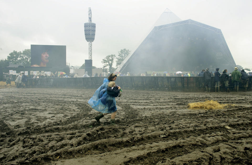 A mother carries her child through the mud during the Glastonbury 2007 mudbath. (Reuters)