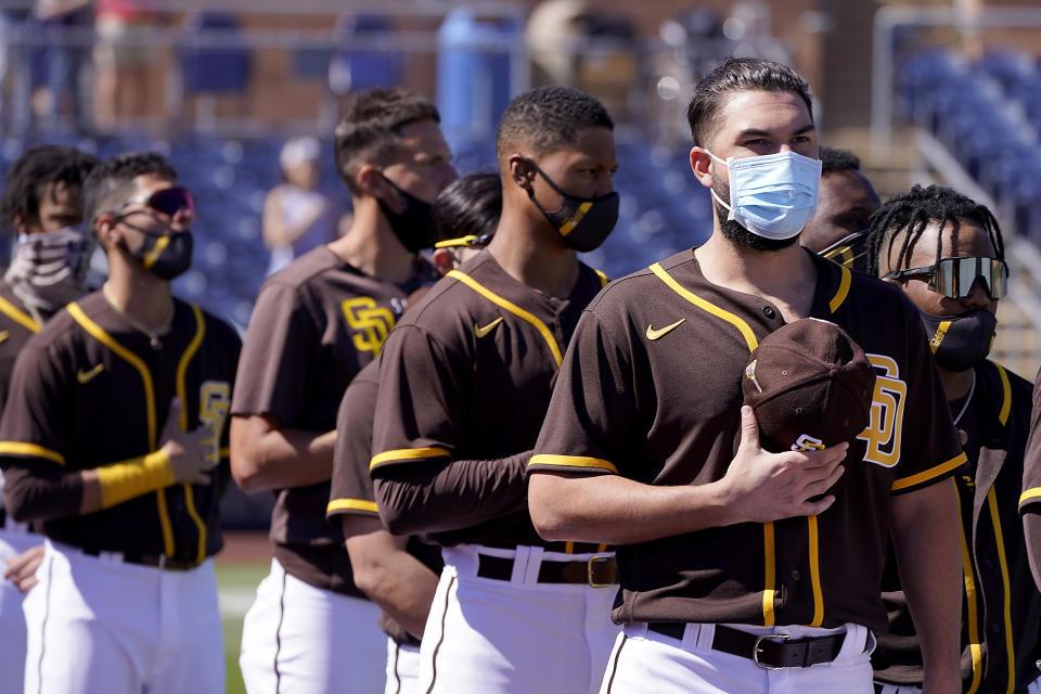 Players for the San Diego Padres stand for the national anthem before a spring training baseball game against the Chicago Cubs, Monday, March 1, 2021, in Peoria, Ariz. (AP Photo/Charlie Riedel)