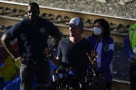 California Governor Gavin Newsom, center, speaks to reporters wile visiting a Union Pacific railroad site on Thursday, Jan. 20, 2022, in Los Angeles. Gov. Gavin Newsom on Thursday promised statewide coordination in going after thieves who have been raiding cargo containers aboard trains nearing downtown Los Angeles for months, leaving the tracks blanketed with discarded boxes. (AP Photo/Ashley Landis)