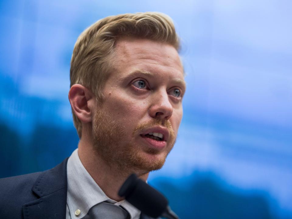 Steve Huffman speaking into a microphone while wearing a blue blazer and a light blue shirt with a grey tie.