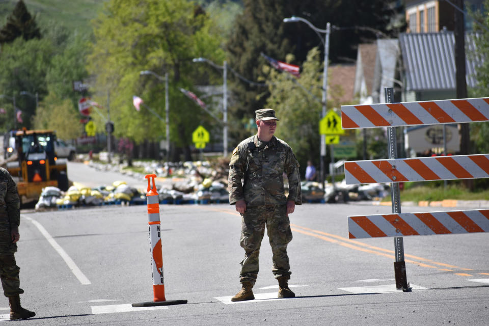 A Montana National Guard soldier is seen next to a barrier blocking the main thoroughfare through Red Lodge, Mont., on Thursday, June 16, 2022, after flooding pummeled parts of the city near Yellowstone National Park. State officials say it could take months to repair area roads that link the tourist-dependent community and the park. (AP Photo/Matthew Brown)