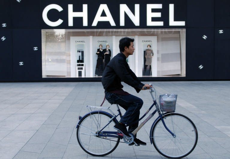 A Chinese man cycles past a luxury boutique in Beijing on October 22, 2009. China's stated aim to narrow the income gulf between its sports-car driving elite and vast numbers who still live in poverty will need radical political and economic changes to work, say economists