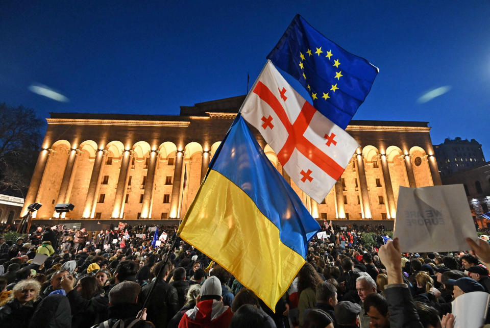 Protesters wave the Georgian, Ukrainian and European flags outside Georgia's Parliament in Tbilisi on March 8, 2023. (Vano Shlamov  / AFP - Getty Images)