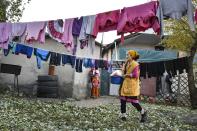 Burul, wife of Kanat Kaliyev's son Adilet, hangs up the laundry to dry at a yard of their family house in Tash Bashat village about 24 kilometers (15 miles) southeast of Bishkek, Kyrgyzstan, Tuesday, Oct. 20, 2020. Political turmoil has gripped Kyrgyzstan over recent years, but life in this quiet village nestled between scenic mountains follows its centuries-old course. (AP Photo/Vladimir Voronin)