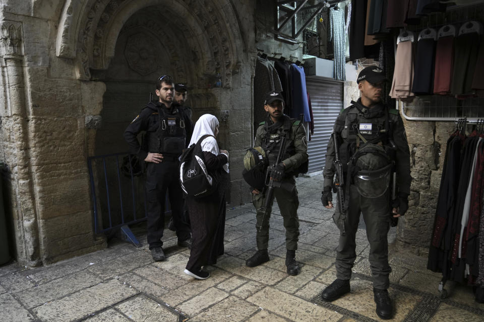 A Muslim woman passes Israeli police at a checkpoint outside of the Al-Aqsa Mosque compound following a raid of the site in the Old City of Jerusalem during the Muslim holy month of Ramadan, Wednesday, April 5, 2023. Palestinian media reported police attacked Palestinian worshippers, raising fears of wider tension as Islamic and Jewish holidays overlap.(AP Photo/Mahmoud Illean)