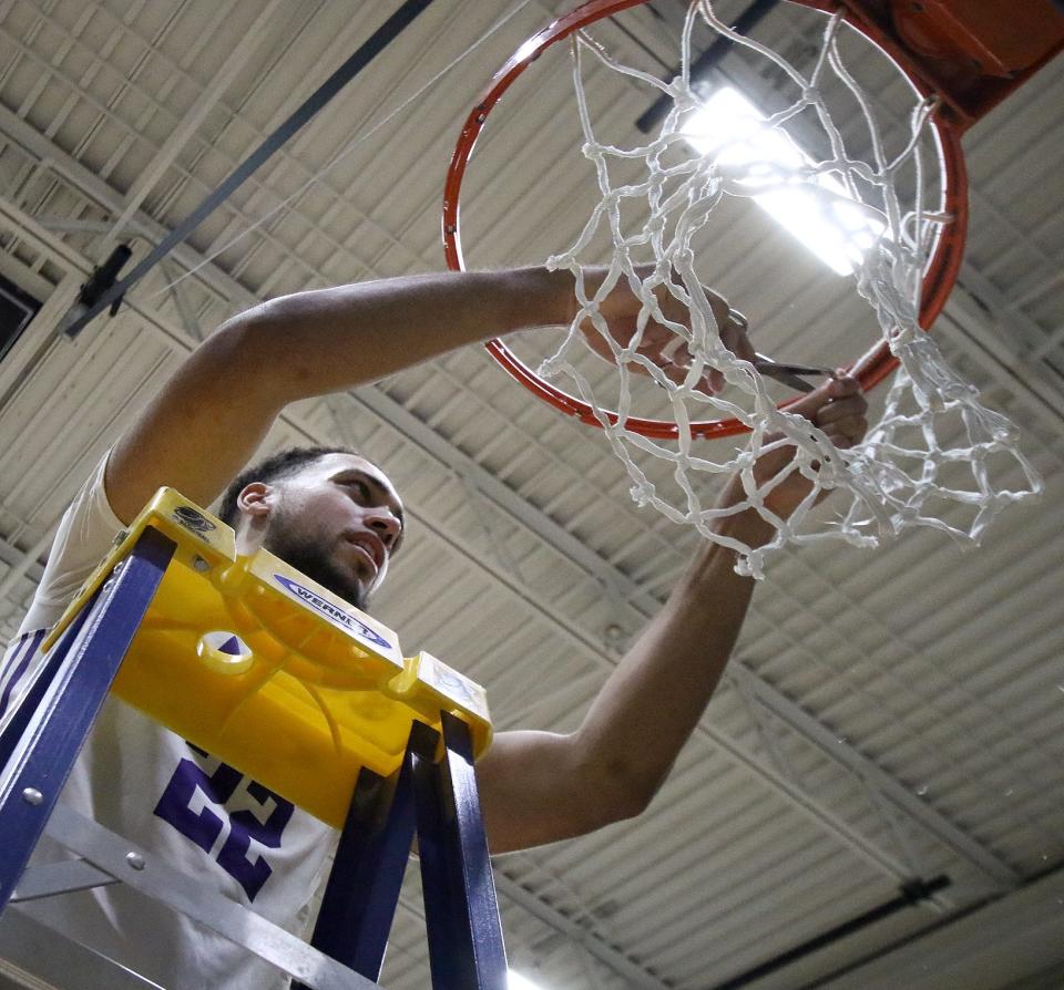 Mount Union's Christian Parker cuts off a piece of the net following an NCAA Division III Elite 8 win, Saturday, March 11, 2023.