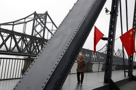 A woman walks across the destroyed bridge over the Yalu River that once linked North Korea's Sinuiju and Dandong in China's Liaoning province, September 10, 2016. REUTERS/Thomas Peter