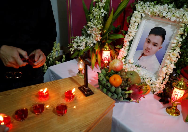 A relative of John Hoang Van Tiep, a victim who was found dead in the back of a British truck last month, lights a candle on his coffin in Nghe An province