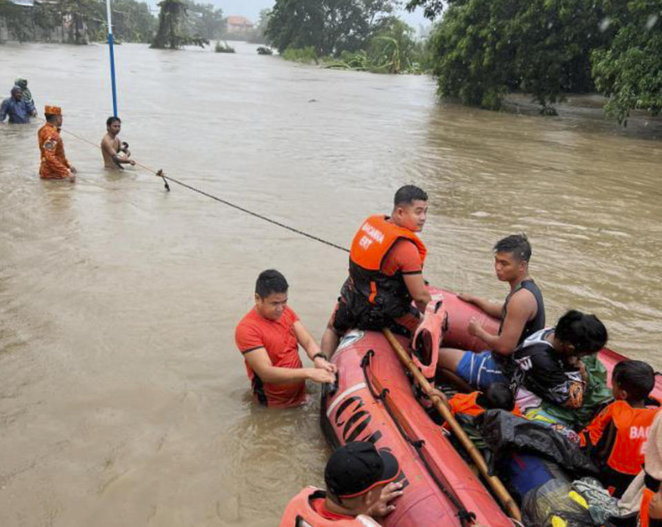 In this photo provided by the Philippine Coast Guard, rescuers use a rubber boat along floodwaters caused by Typhoon Doksuri as they evacuate residents to higher grounds in Bacarra, Ilocos Norte province, northern Philippines on Wednesday July 26, 2023. Typhoon Doksuri ripped off tin roofs from homes, engulfed low-lying villages in flood, knocked down power and displaced more than 12,000 people Wednesday as it smashed into a small island and lashed northern Philippine provinces overnight with ferocious wind and rain, officials said. (Philippine Coast Guard via AP)