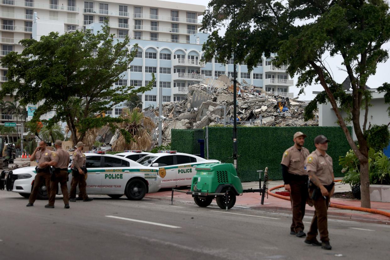 Miami-Dade police officers helping with the search and rescue stand near the completely collapsed 12-story Champlain Towers South on July 6, 2021, in Surfside, Fla. The portion of the building left standing after the deadly June 24 collapse was demolished Sunday night ahead of the approach of Tropical Storm Elsa.