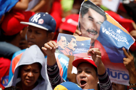 A supporter of Venezuela's President Nicolas Maduro holds a banner depicting Maduro and late President Hugo Chavez, during a campaign rally in Caracas, Venezuela, May 17, 2018. The banner reads: "Together, everything is possible". REUTERS/Carlos Garcia Rawlins