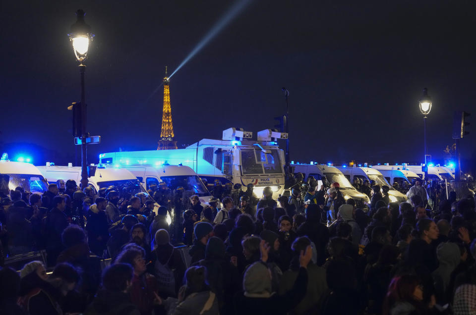 Manifestantes durante una protesta frente a una hilera de vehículos de la policía, el viernes 17 de marzo de 2023, en París. (AP Foto/Lewis Joly)