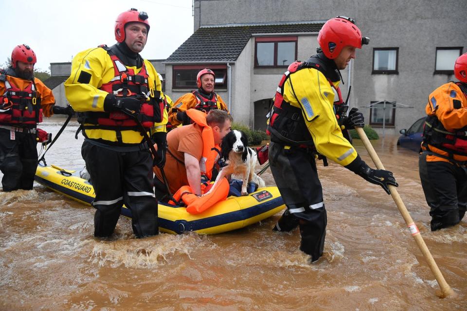 A couple and their dog are rescued by a coast guard team from a flooded street in Brechin, northeast Scotland (AFP via Getty Images)