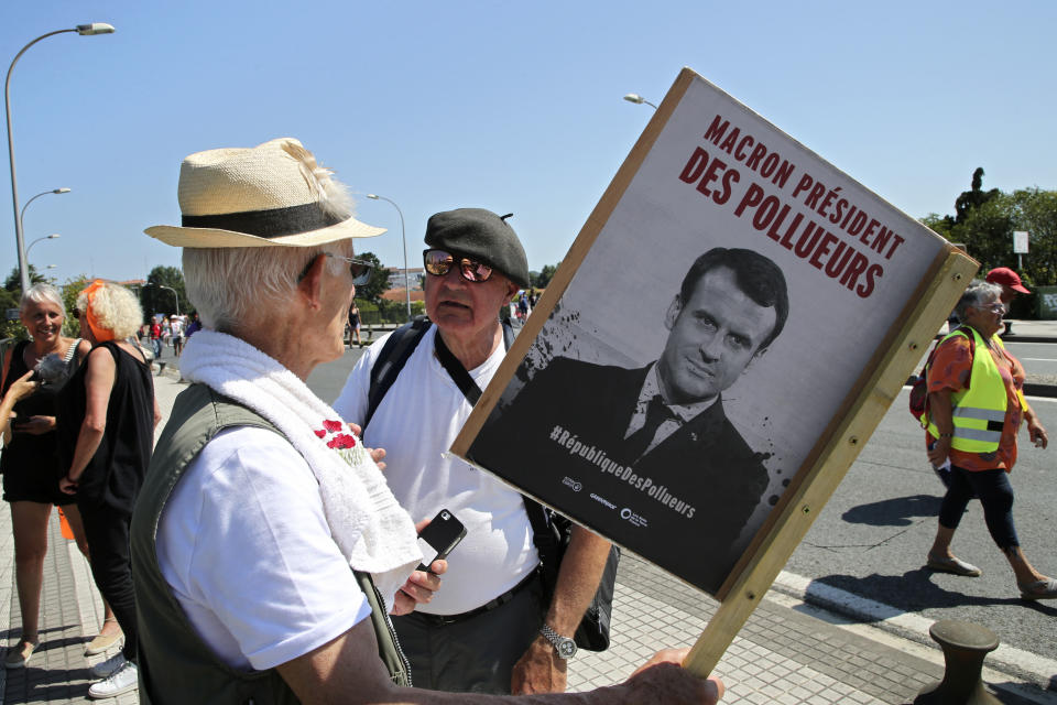 A protestor hold a picture of French President Emmanuel Macron with the words "Macron Polluter President" while crossing a bridge from Hendaye, France, to Irun, Spain, during a protest Saturday, Aug. 24, 2019. World leaders and protesters are converging on the southern French resort town of Biarritz for the G-7 summit. President Donald Trump will join host French President Emmanuel Macron and the leaders of Britain, Germany, Japan, Canada and Italy for the annual summit in the nearby resort town of Biarritz. Banner in Basque, French and Spanish reads, "No to G7, Creating another world". (AP Photo/Bob Edme)