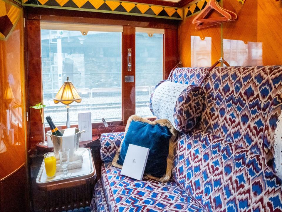 a train cabin with wood finishings and a plush red and blue couch.